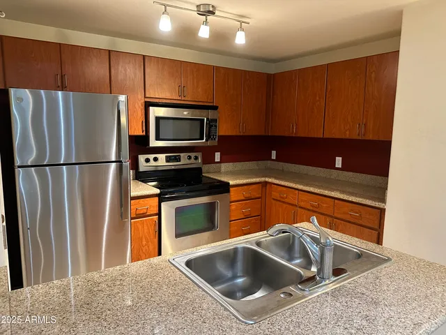 a kitchen with stainless steel appliances granite countertop a sink refrigerator and microwave