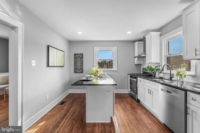 a kitchen with granite countertop a sink cabinets stainless steel appliances and a window
