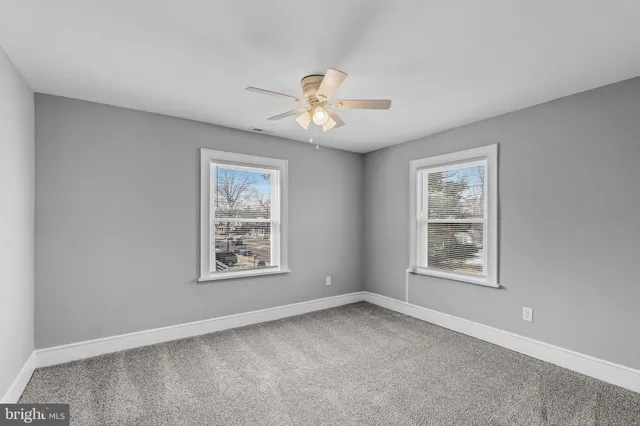 a view of a white house with a large tree and wooden fence