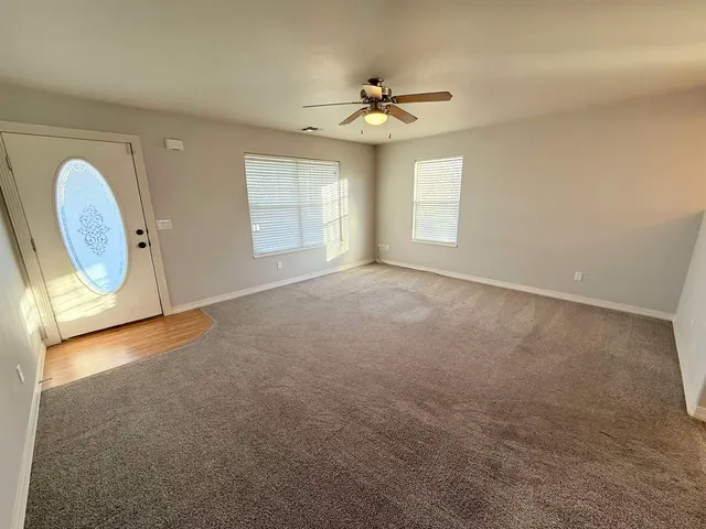 an empty room with windows and chandelier fan
