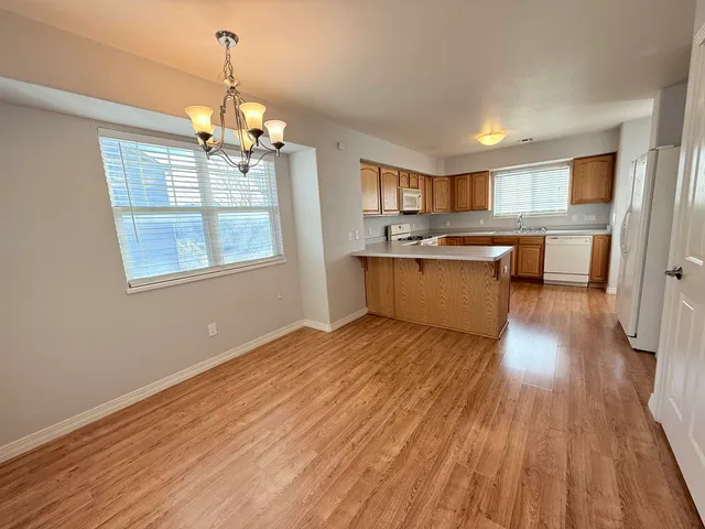 a view of a kitchen with granite countertop wooden floor stainless steel appliances and a chandelier
