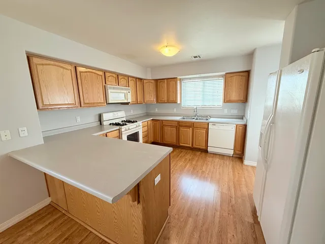 a kitchen with stainless steel appliances a refrigerator a sink dishwasher a stove with wooden floor and cabinets