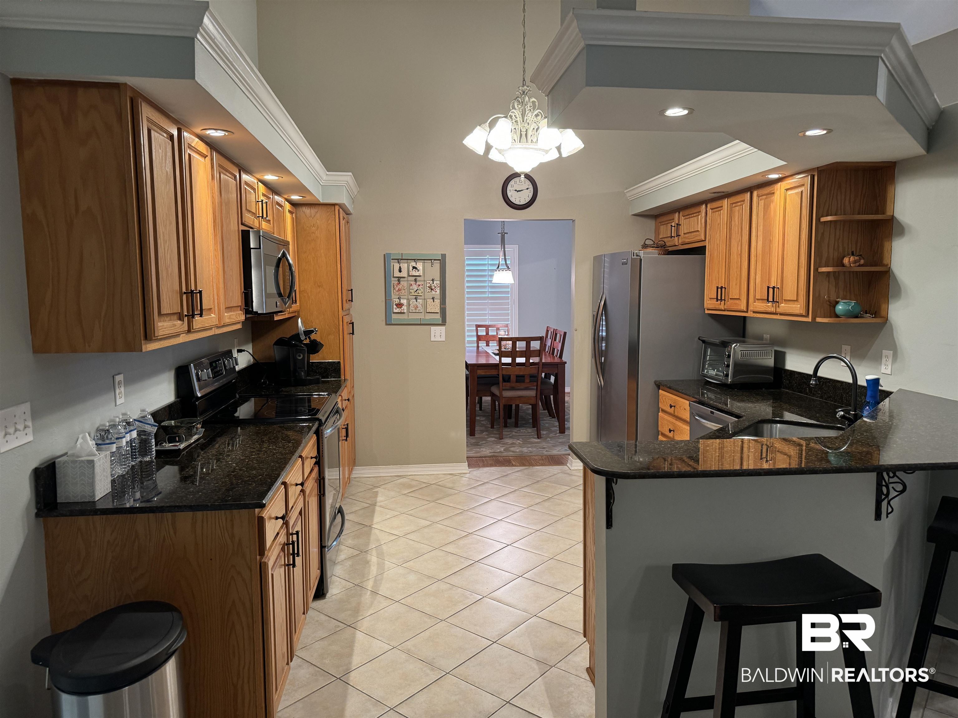 9139 Clubhouse Drive Foley, AL 36535 - Photo 17 of 30 Kitchen featuring stainless steel appliances, kitchen peninsula, hanging light fixtures, light tile patterned floors, and a notable chandelier