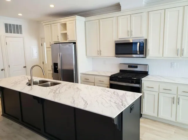 a kitchen with stainless steel appliances granite countertop a sink a stove a microwave and a refrigerator