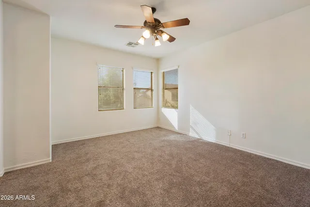 an empty room with windows and ceiling fan