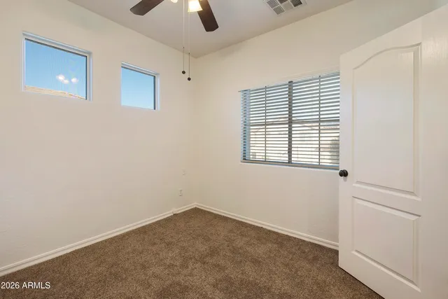 an empty room with a window and a ceiling fan