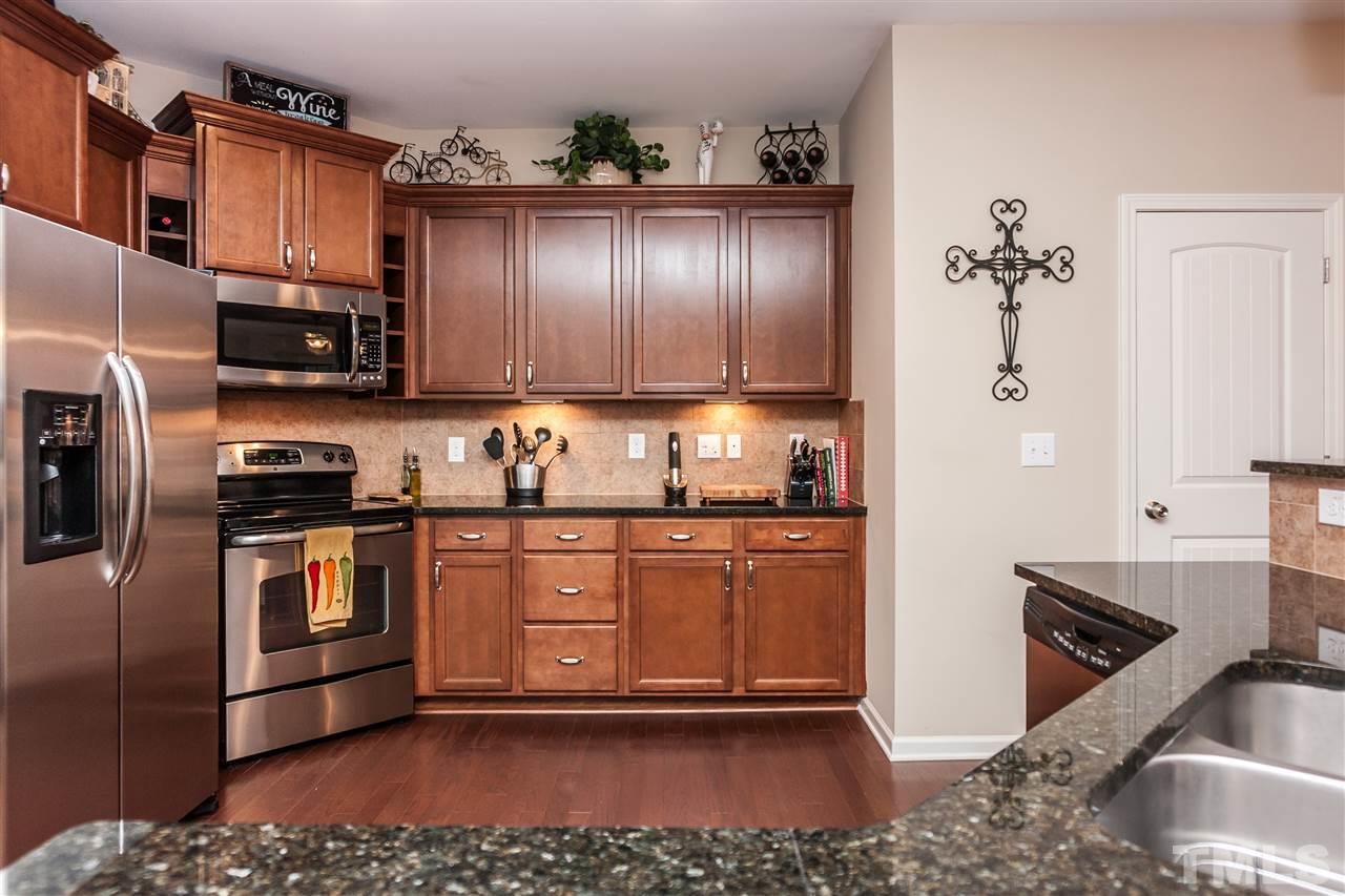 1306 Still Monument Way Raleigh, NC 27603 - Photo 7 of 25 a kitchen with stainless steel appliances granite countertop a refrigerator a stove and a sink with wooden floor