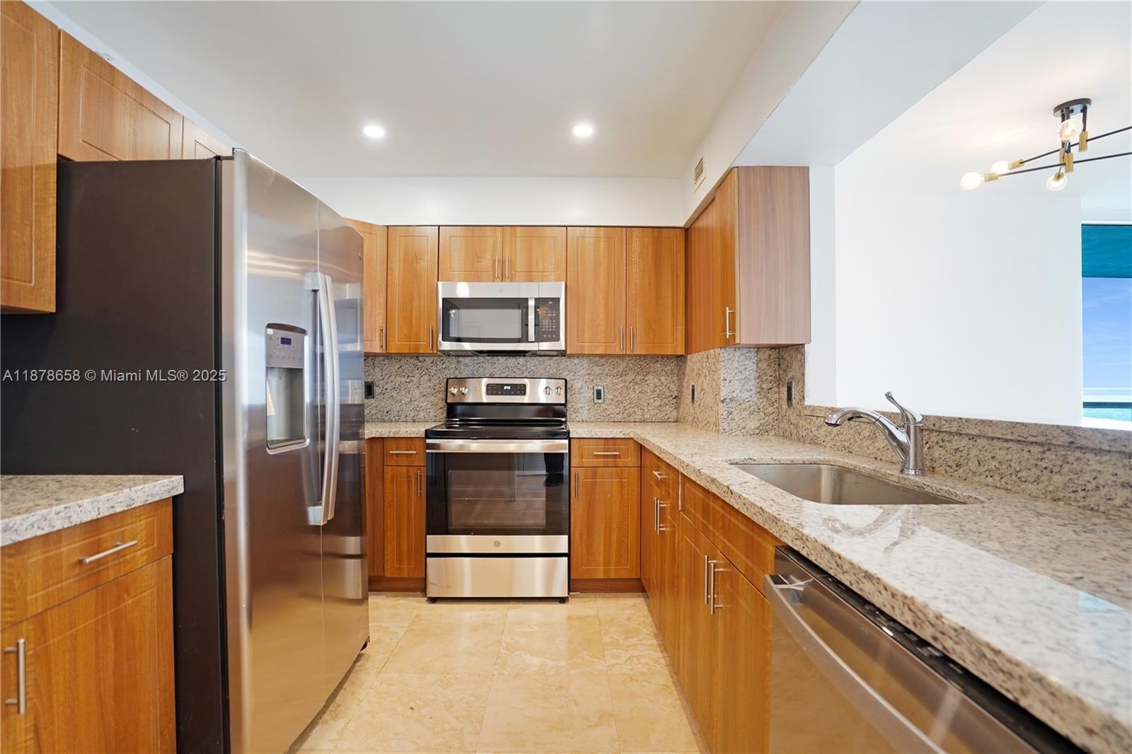 5101 Collins Avenue, Unit 14A Miami Beach, FL 33140 - Photo 4 of 14 a kitchen with kitchen island granite countertop a sink stainless steel appliances and cabinets
