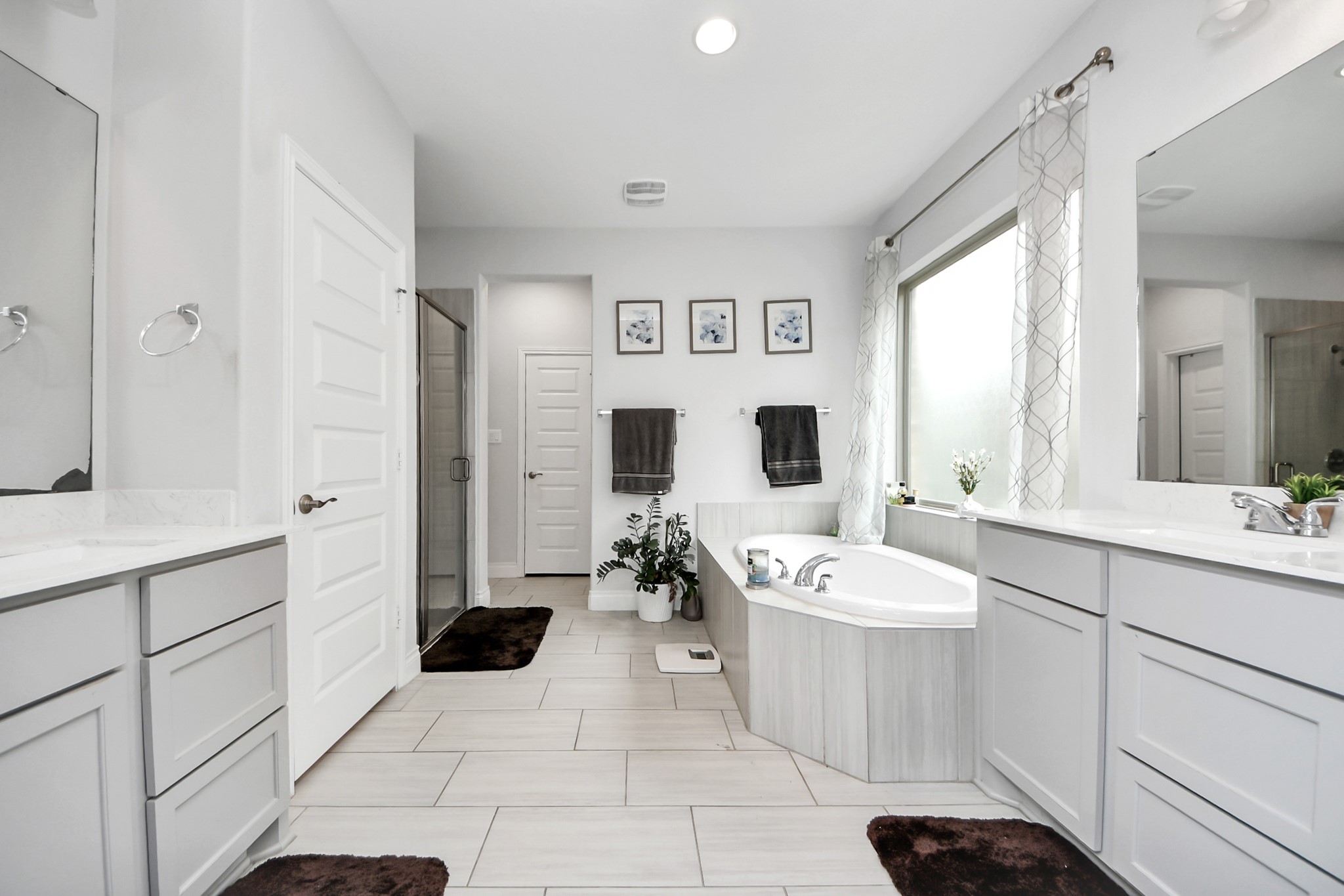 2242 Bayleaf Manor Drive Manvel, TX 77578 - Photo 30 of 50 a spacious bathroom with a double vanity sink a mirror a window and a bathtub