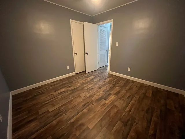 a view of an empty room with window and wooden floor