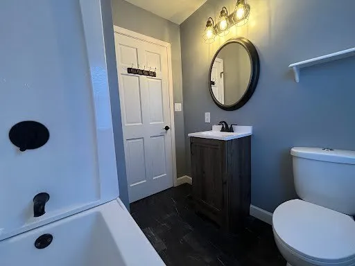 a bathroom with a granite countertop toilet sink and mirror