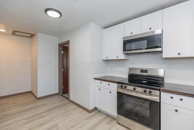 a kitchen with stainless steel appliances white cabinets and a stove top oven