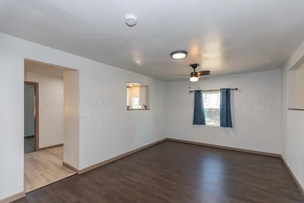 an empty room with wooden floor chandelier and windows
