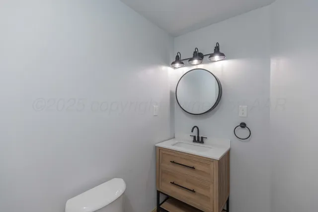 a bathroom with a toilet sink vanity and mirror