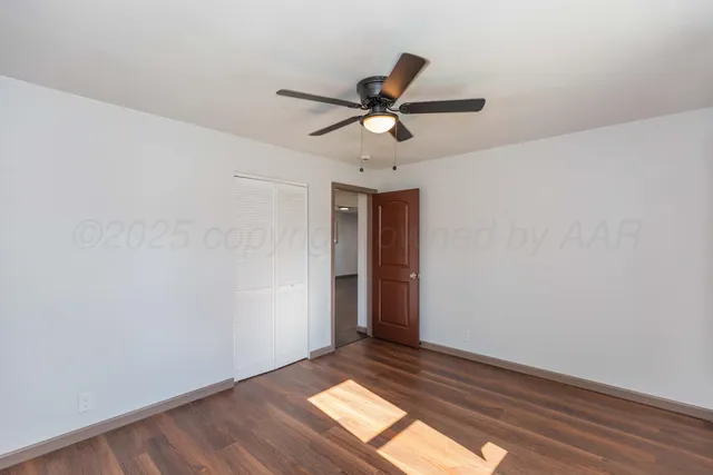 a view of empty room with wooden floor and fan