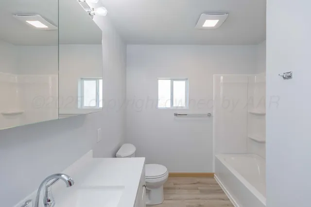 a bathroom with a toilet a sink a mirror and bathtub