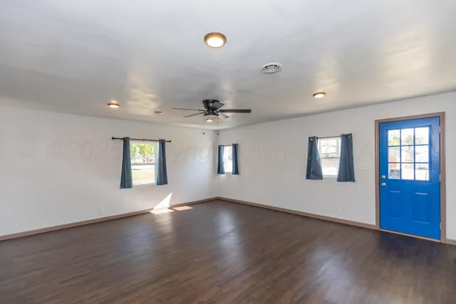 a view of an empty room with a window and wooden floor