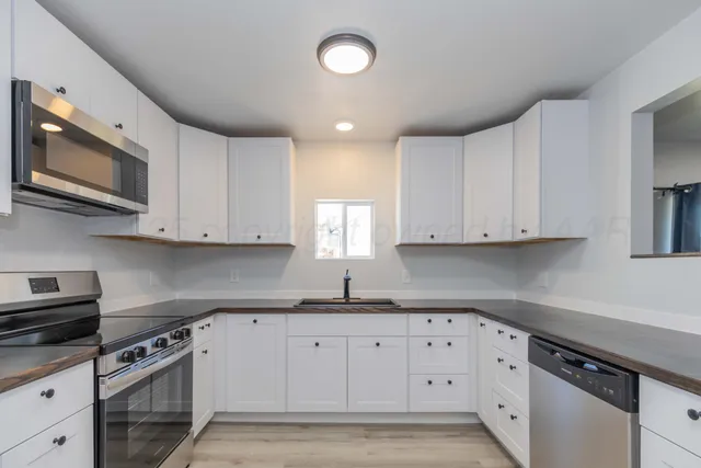 a kitchen with white cabinets stainless steel appliances and sink