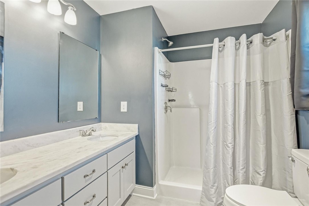 745 Dave Nix Road Seneca, SC 29678 - Photo 12 of 23 A well-lit bathroom features a long marble-topped vanity with double sinks and a clean shower stall.