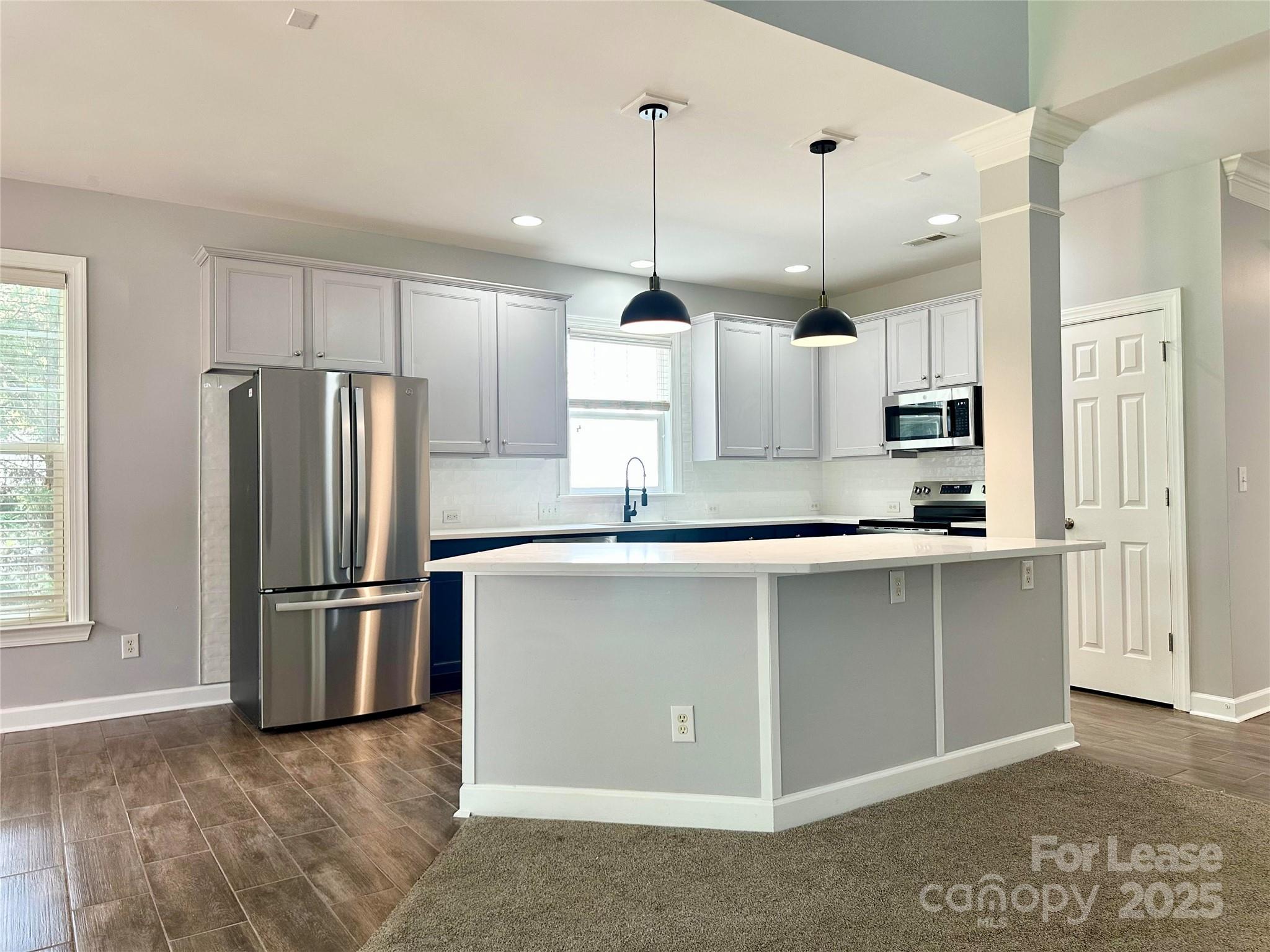 a kitchen with stainless steel appliances granite countertop a refrigerator a sink a stove a microwave and wooden floors