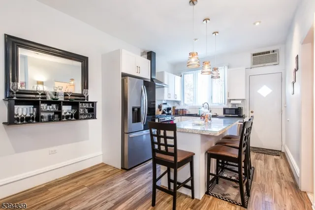 a kitchen with stainless steel appliances a dining table chairs and wooden floor