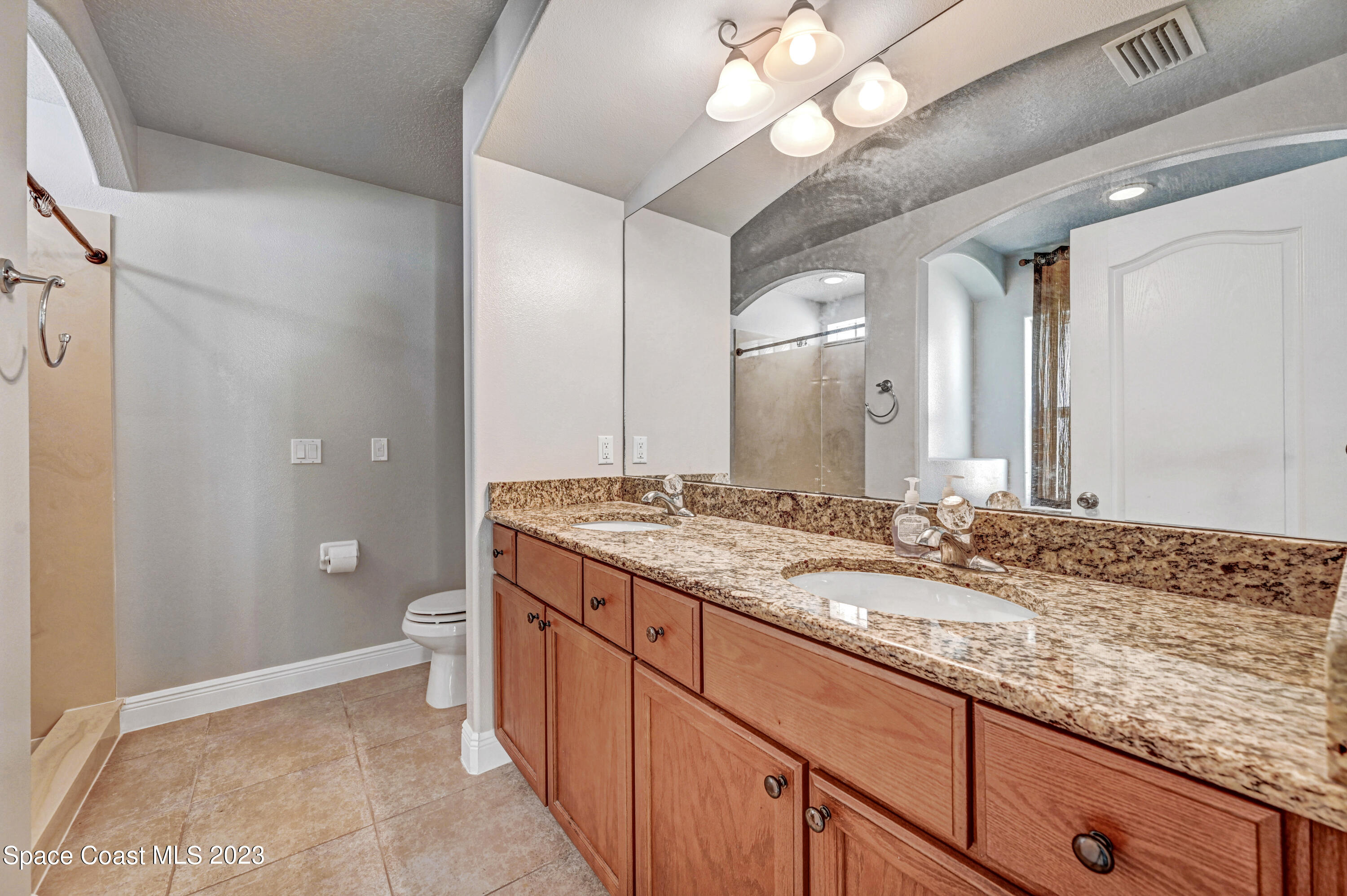 1202 Becket Place Melbourne, FL 32940 - Photo 24 of 56 a bathroom with a granite countertop sink a toilet and a large mirror
