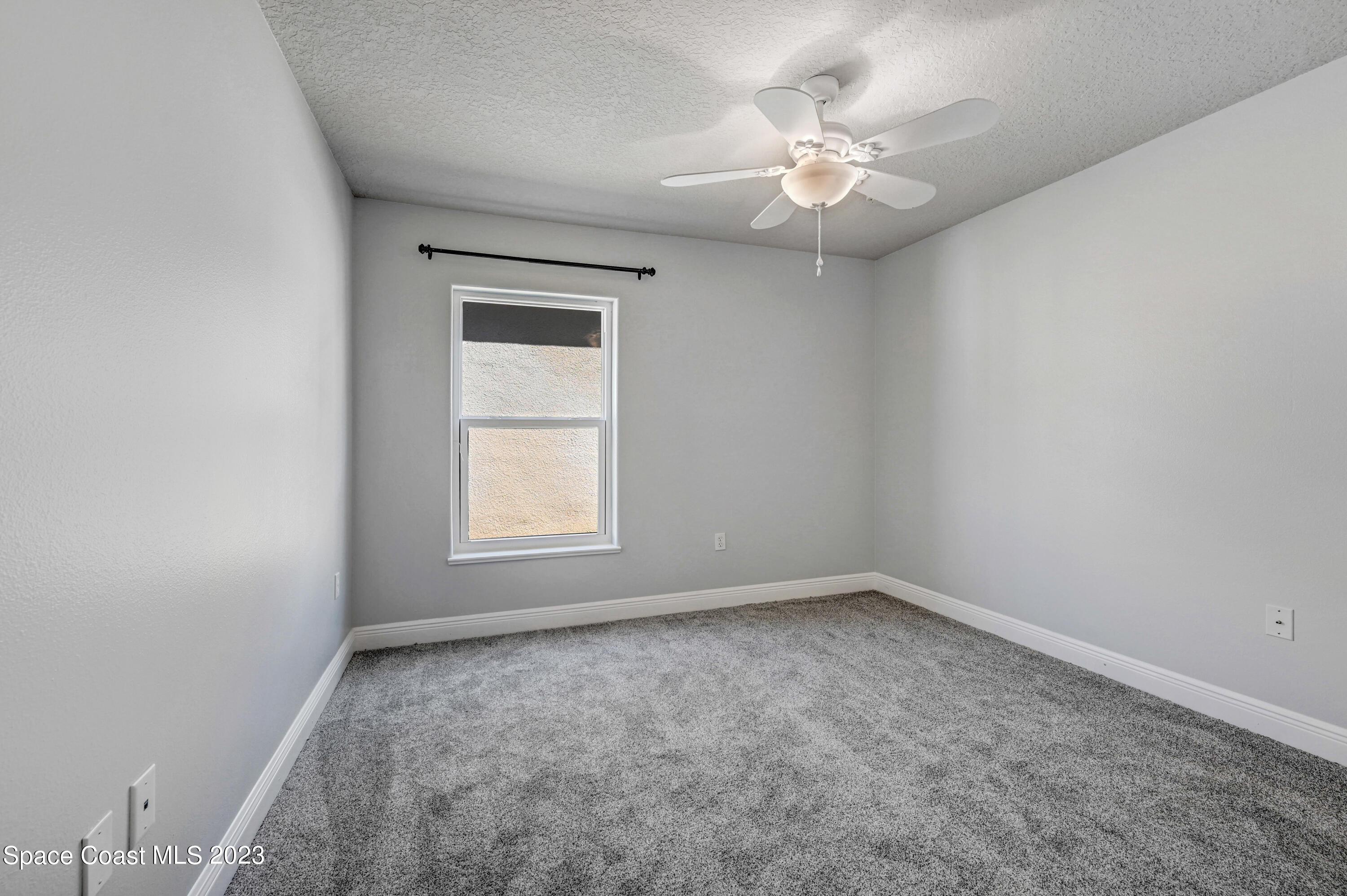 1202 Becket Place Melbourne, FL 32940 - Photo 26 of 56 an empty room with a chandelier fan and windows