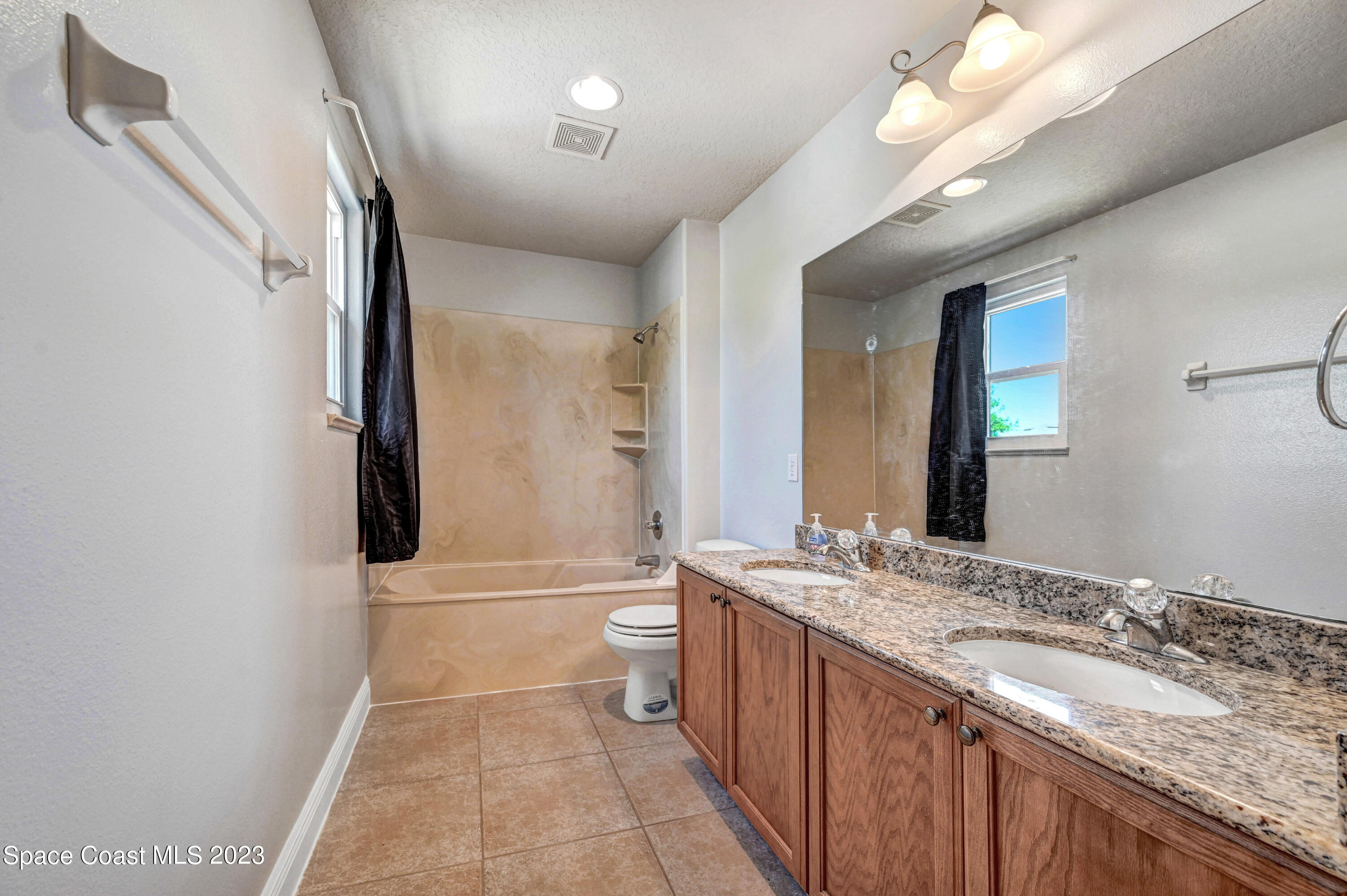 1202 Becket Place Melbourne, FL 32940 - Photo 34 of 56 a bathroom with a granite countertop sink a toilet and a mirror