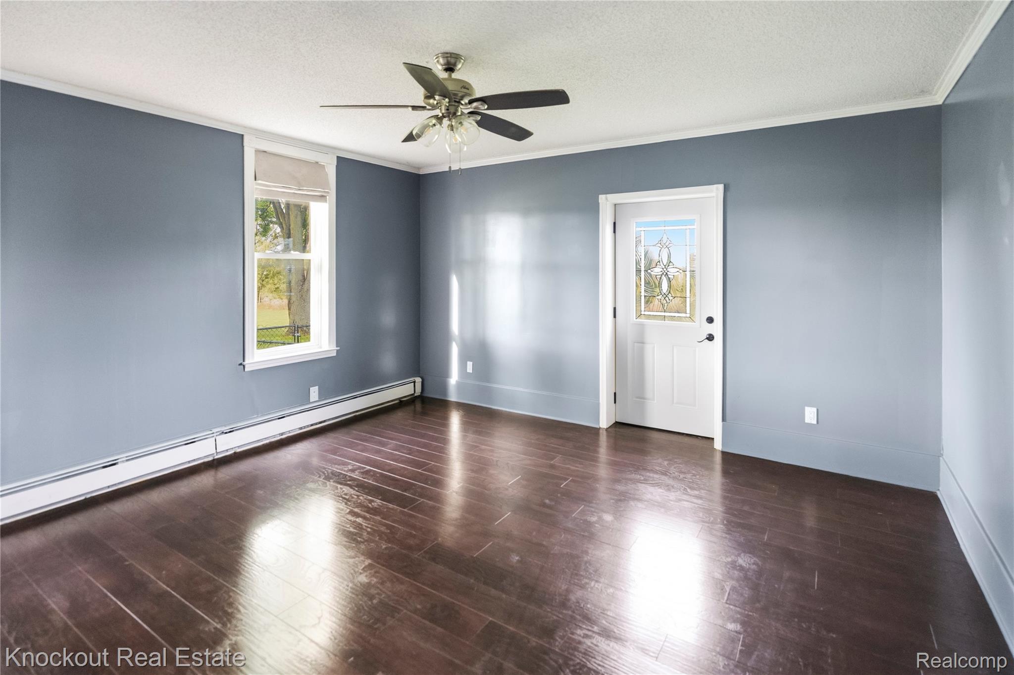 5750 Maple Road Frankenmuth, MI 48734 - Photo 10 of 60 Wood-finish flooring, ceiling fan with integrated lighting, white trim, and a white paneled door with a decorative glass insert