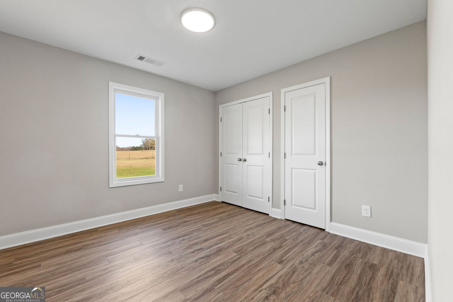 166 Mathews Road Milner, GA 30257 - Photo 22 of 32 an empty room with wooden floor and windows
