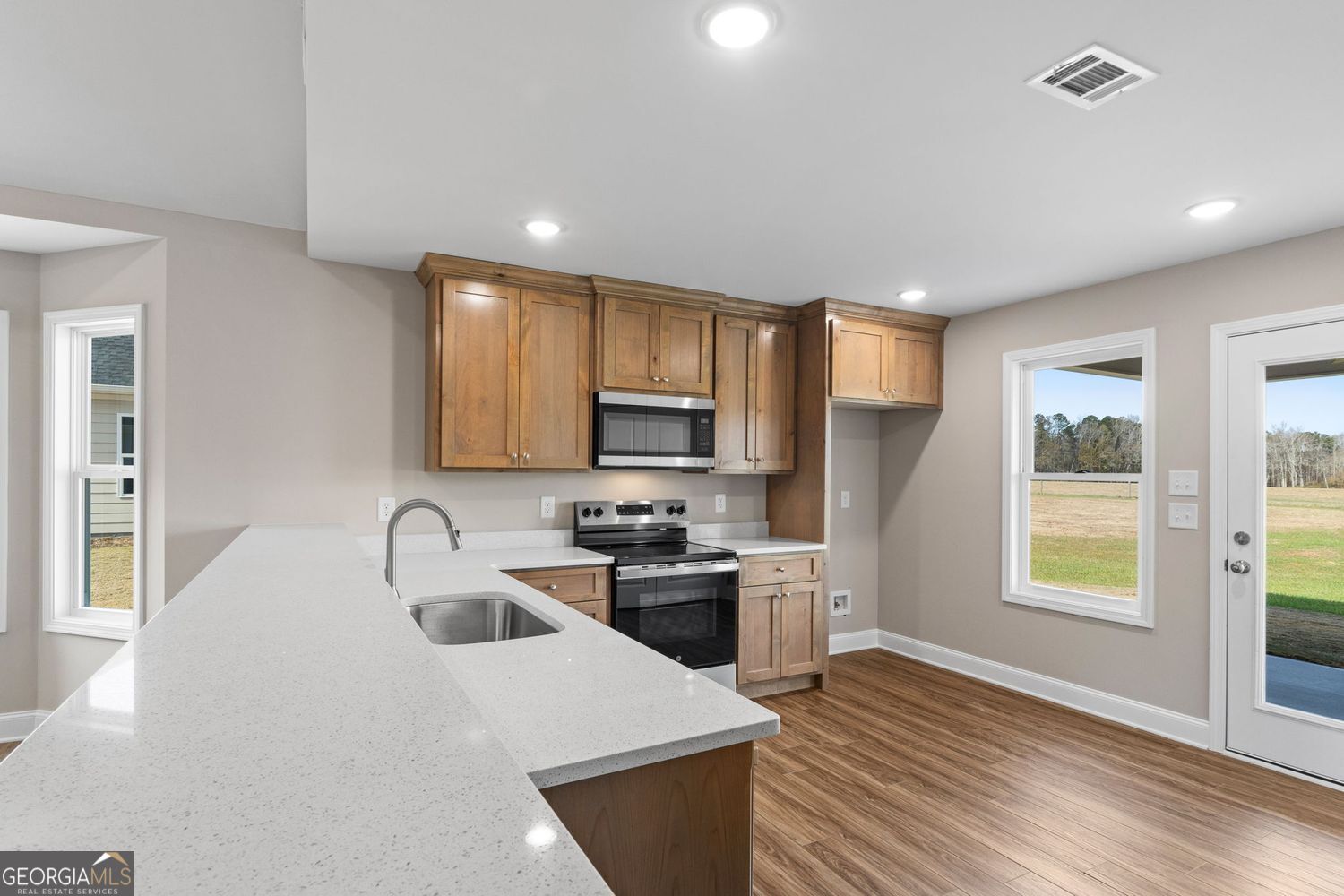 166 Mathews Road Milner, GA 30257 - Photo 10 of 32 a kitchen with stainless steel appliances a sink a stove a refrigerator cabinets and a window