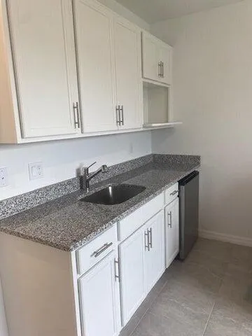 a kitchen with granite countertop white cabinets and sink