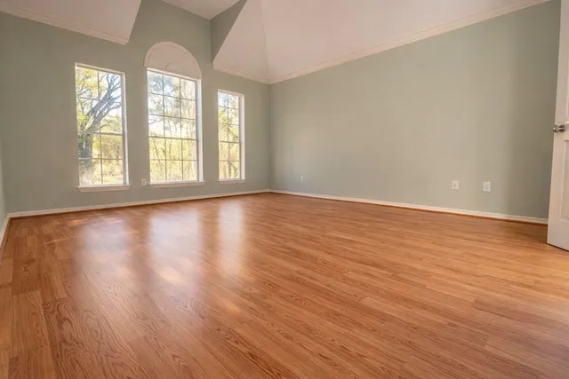 a view of an empty room with wooden floor and a window