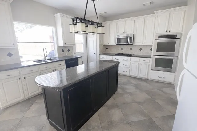 a kitchen with stainless steel appliances granite countertop a sink a stove a refrigerator a center island with wooden cabinets and floor