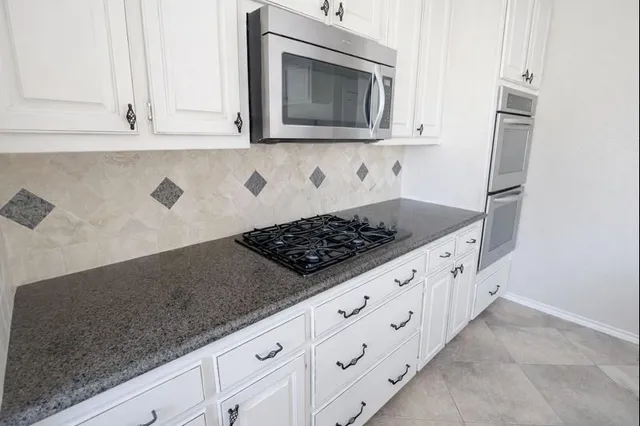 a kitchen with granite countertop white cabinets stainless steel appliances and sink
