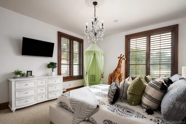 a spacious bedroom with a bed a chandelier and a flat screen television