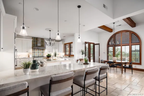 a dining room with furniture a chandelier and kitchen view