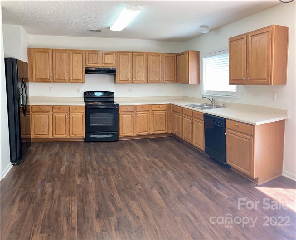 10619 Bedlington Road Charlotte, NC 28278 - Photo 8 of 26 a kitchen with stainless steel appliances wooden floors and wooden cabinets