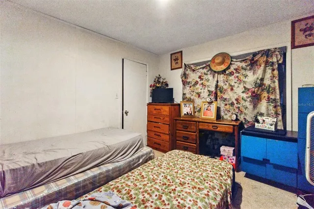 a bedroom with a bed and dresser with wooden floor