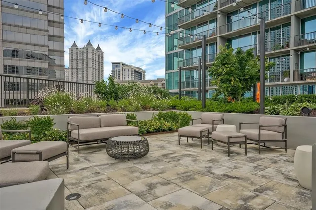 a view of a patio with couches and a fire pit and wooden fence
