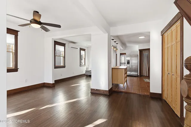 a view of a livingroom with wooden floor a ceiling fan and windows