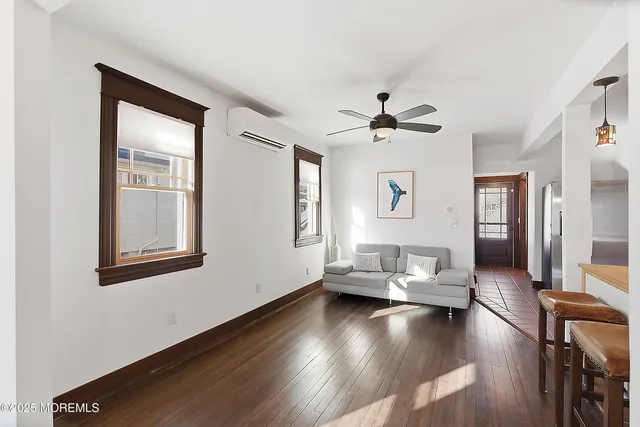 a living room with couches and a ceiling fan with wooden floor