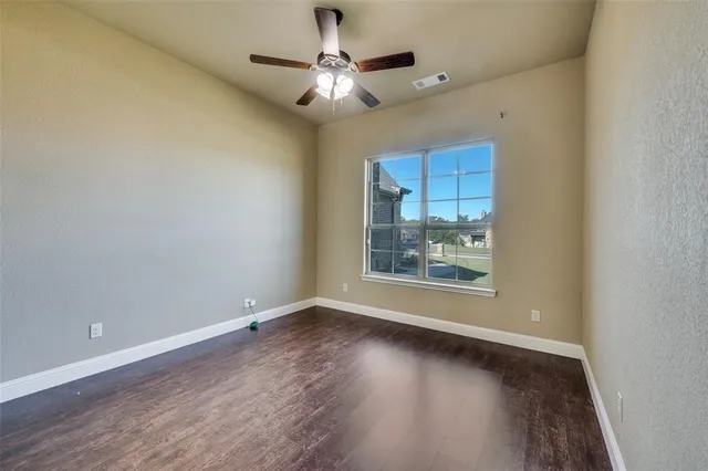 an empty room with wooden floor chandelier fan and windows