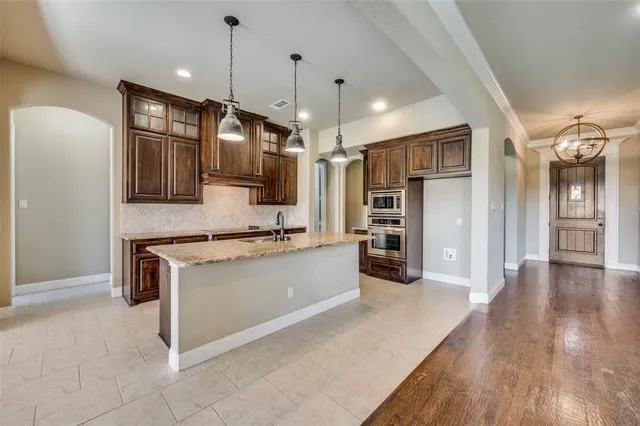 a kitchen with stainless steel appliances granite countertop a refrigerator a oven and a sink with granite countertops