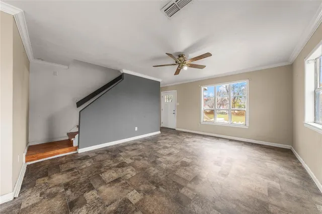 an empty room with windows and ceiling fan