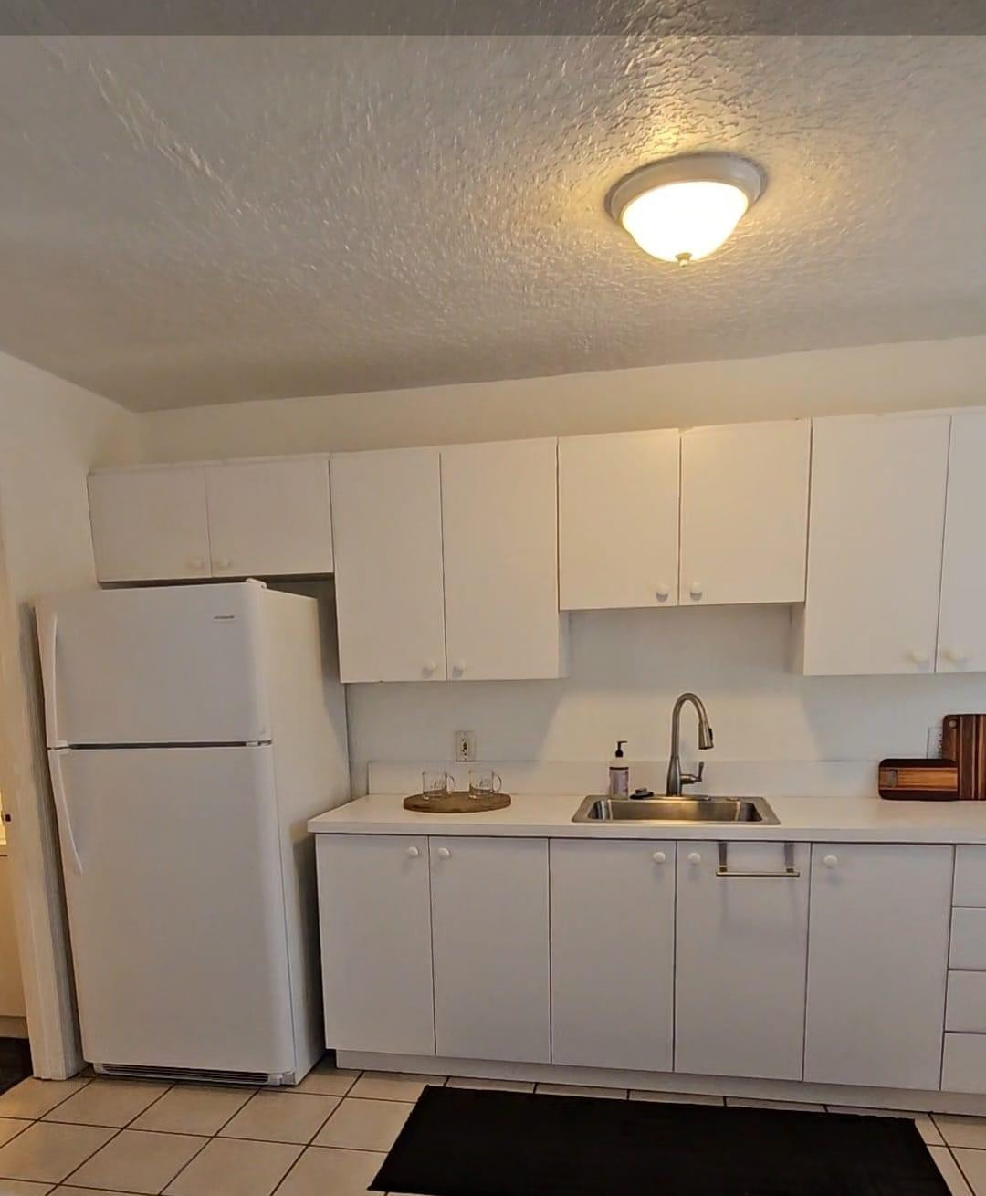 1021 Southeast Monterey Road, Unit 139 Stuart, FL 34994 - Photo 6 of 9 a kitchen with a refrigerator sink and cabinets