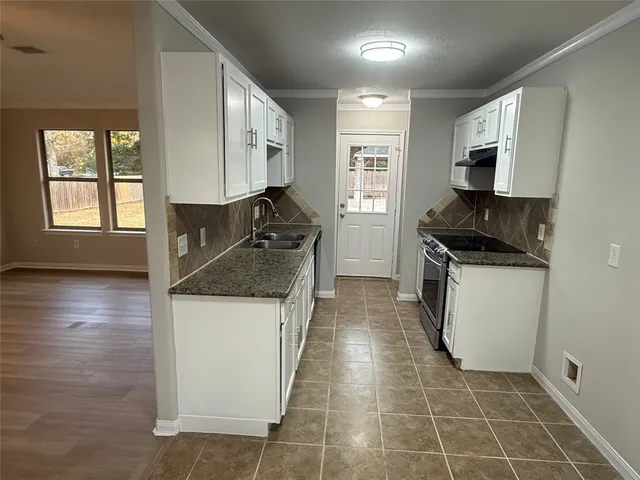 a kitchen with granite countertop a stove top oven and cabinets