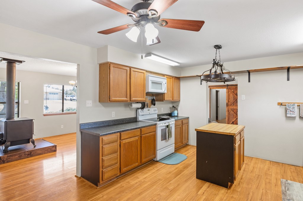 64 Quail Run Harper, TX 78631 - Photo 11 of 25 a kitchen with stainless steel appliances granite countertop a sink a stove top oven a chimney with wooden floor and cabinets