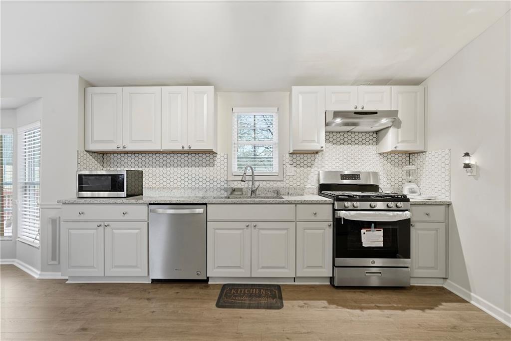 1295 Double Bridges Road Winder, GA 30680 - Photo 9 of 57 a kitchen with stainless steel appliances granite countertop a stove and white cabinets