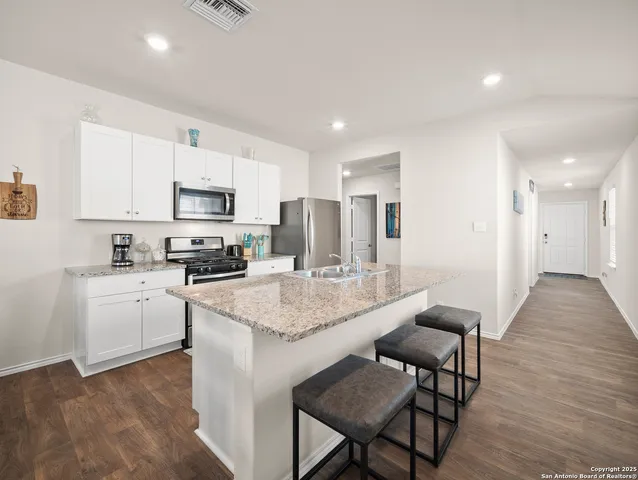 a kitchen with sink a microwave cabinets and wooden floor